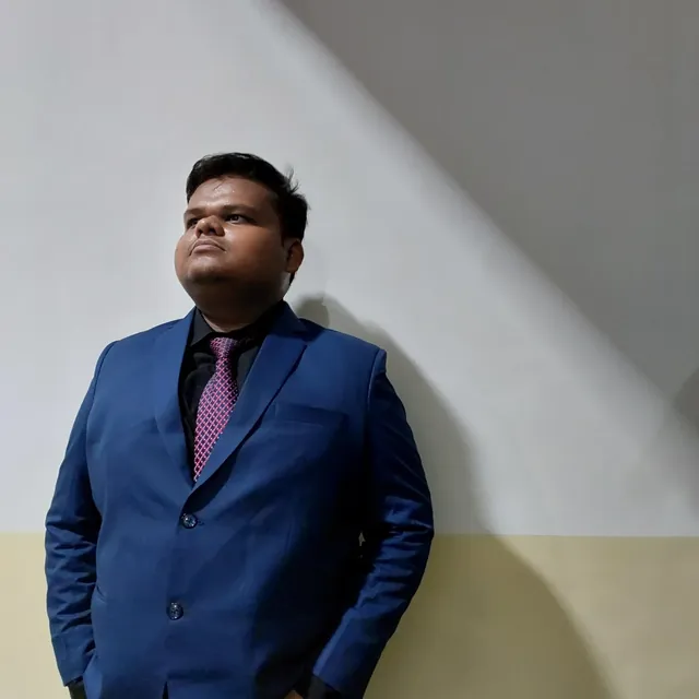 Aditya leaning on a wall, looking up into the light